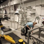 Співробітниця клінінгової компанії Юнона використовує професійний пилосос для знепилення торгових стелажів під час прибирання магазину після ремонту.