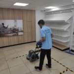 Співробітник клінінгової компанії Юнона виконує глибоке машинне чищення підлоги роторною машиною в торговому приміщенні.
