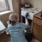 Співробітниця клінінгової компанії Юнона у фірмовій футболці ретельно миє газову плиту та духовку під час генерального прибирання кухні.