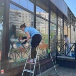 Співробітниці клінінгової компанії Юнона миють великі фасадні вікна та видаляють графіті з вітрини комерційного приміщення.